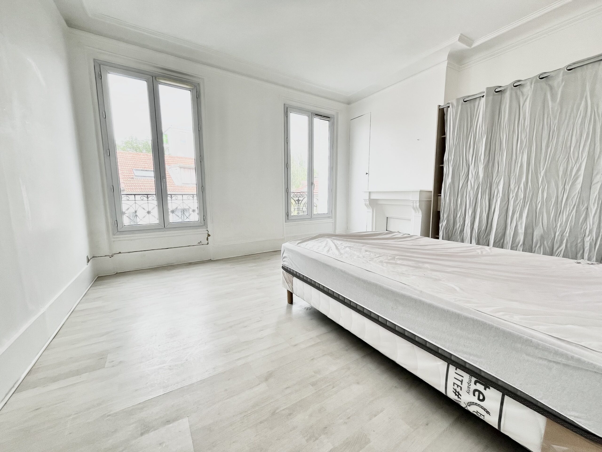 Vue chambre du T3 meublé à Noisy le sec avec lit, armoire, et 2 fenêtres sur presque toute la hauteur