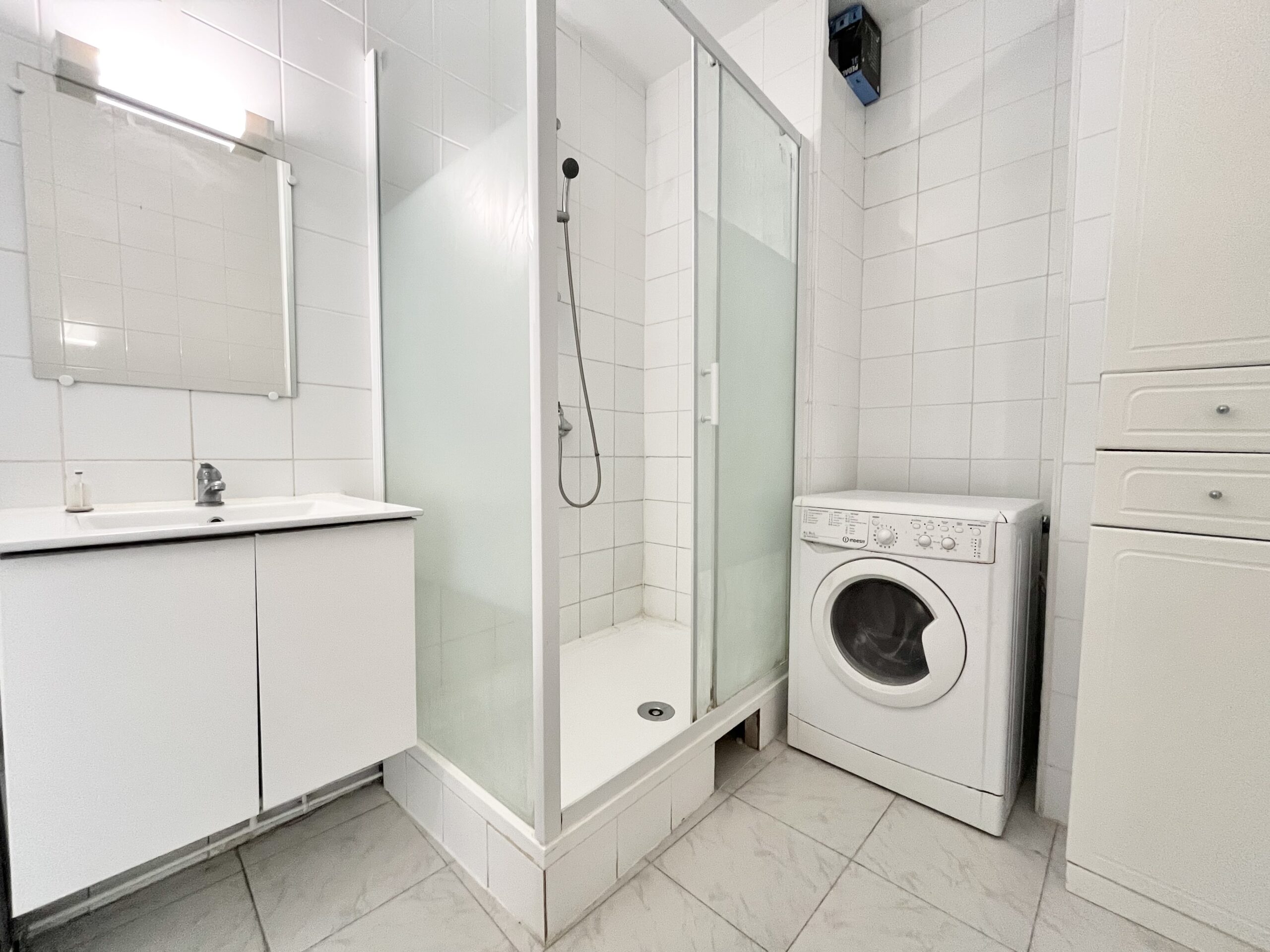 Salle de bain avec douche, vasque et rangement et machine à laver